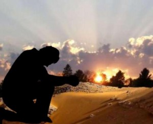 Image of a Pastor praying against a sunset.